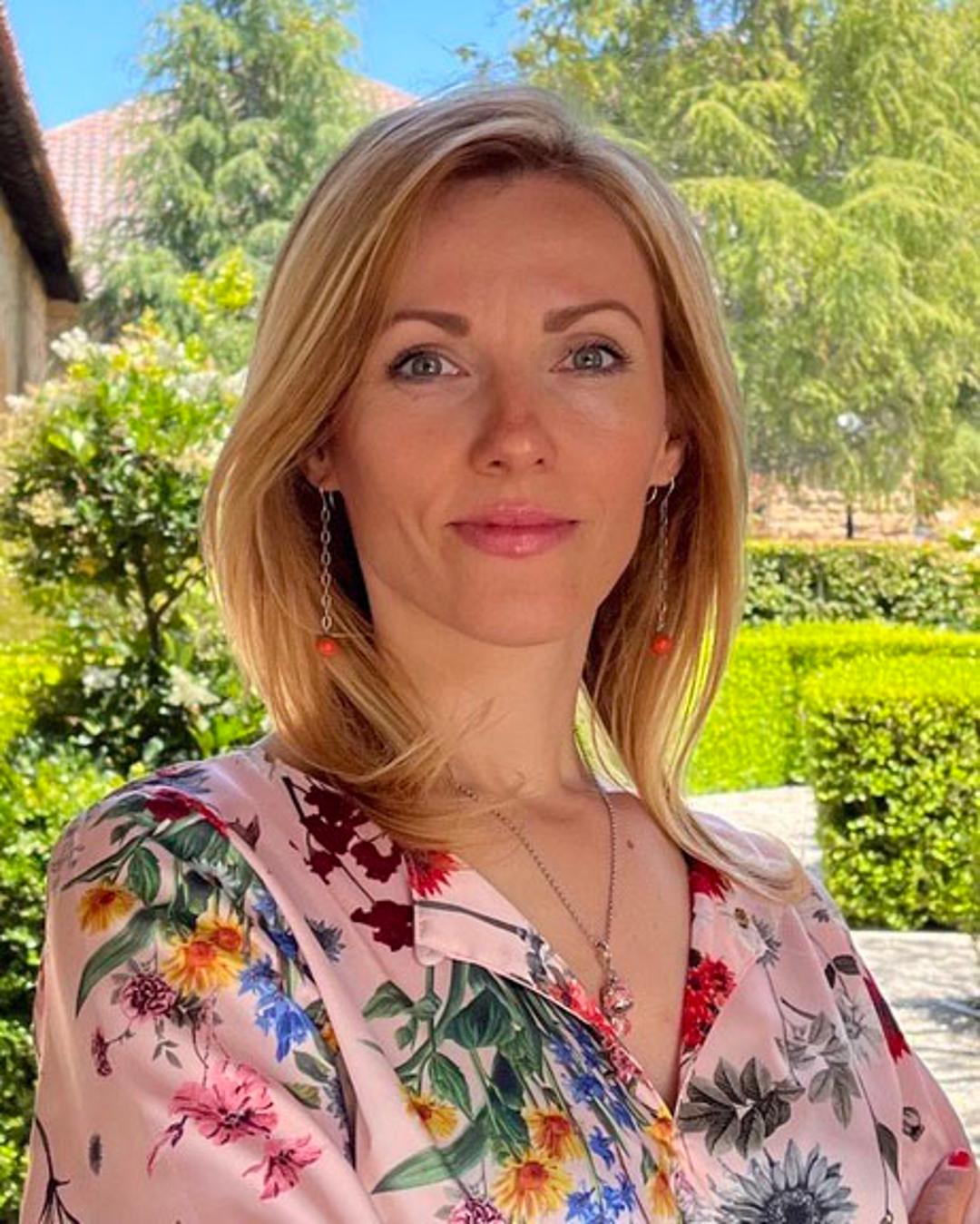 Woman with a blouse with flowers is standing in a garden.