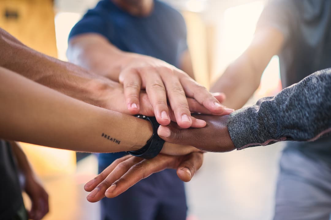 Office employee group with hands in to show collaboration, trust and motivation for corporate job success.