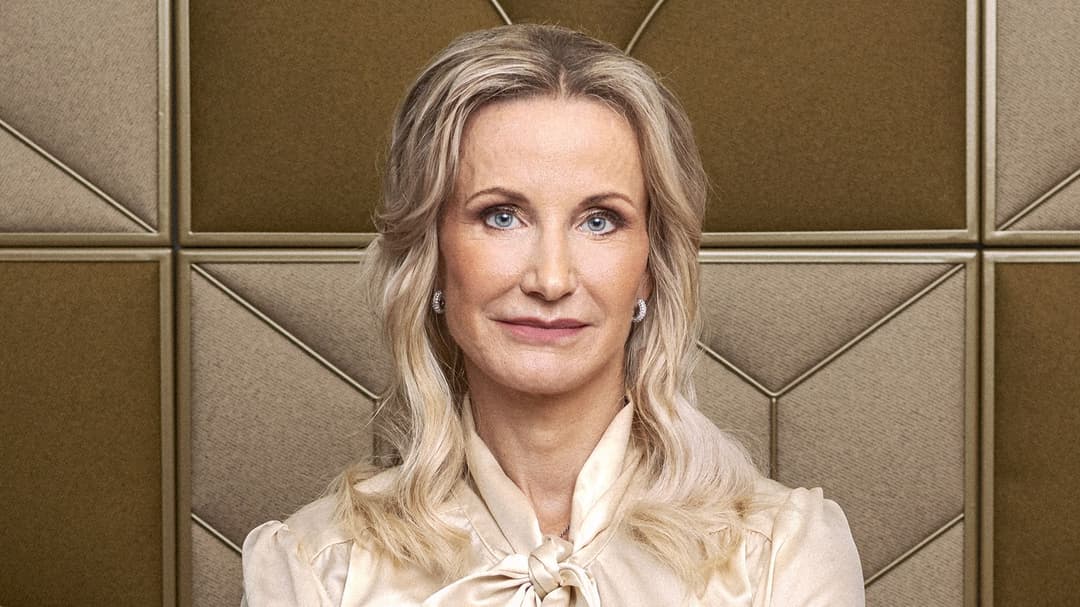 Porträttbild av kvinna med ljust hår och blus som står med armarna i kors.