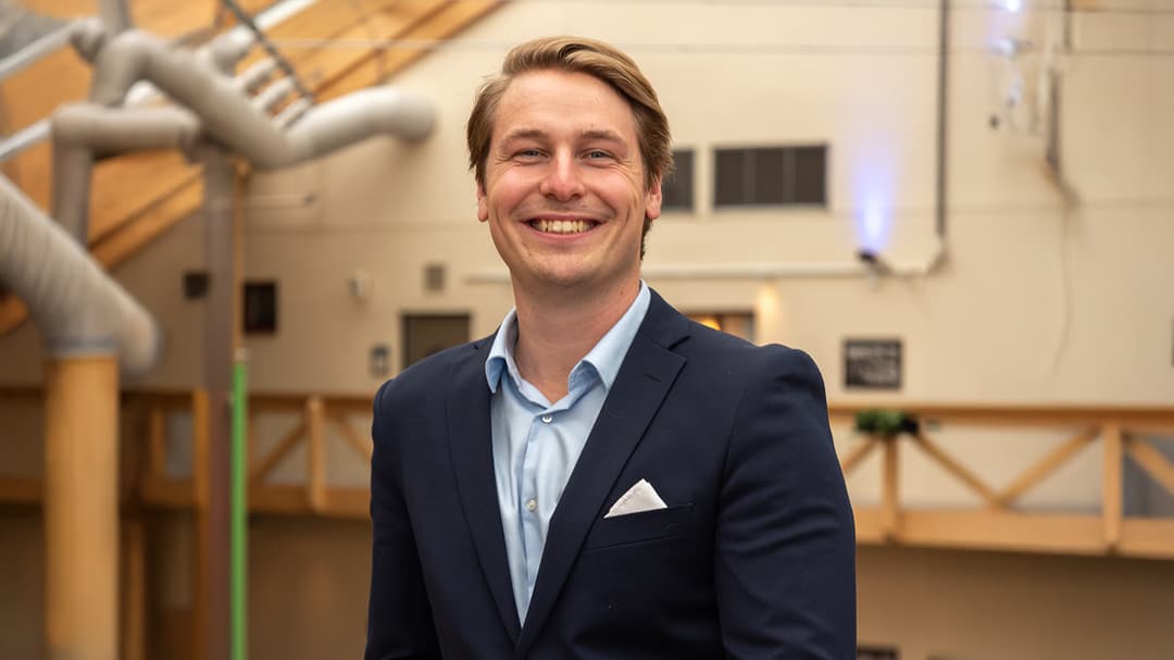 A man in a drak jacket smiles at the camera