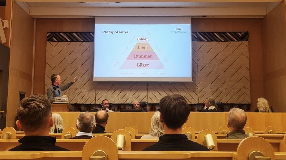 Människor sittandes i en föreläsningssal, lyssnandes till en föreläsare