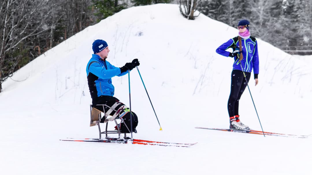 man åker sitski med kvinna på längdskidor