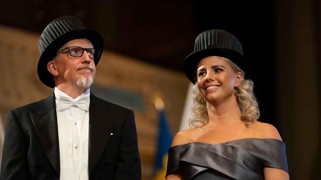 Två finklädda personer som bär varsin doktorshatt.
