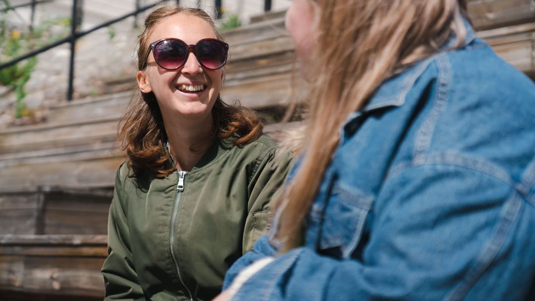 Två studenter som sitter och pratar i en trappa. 