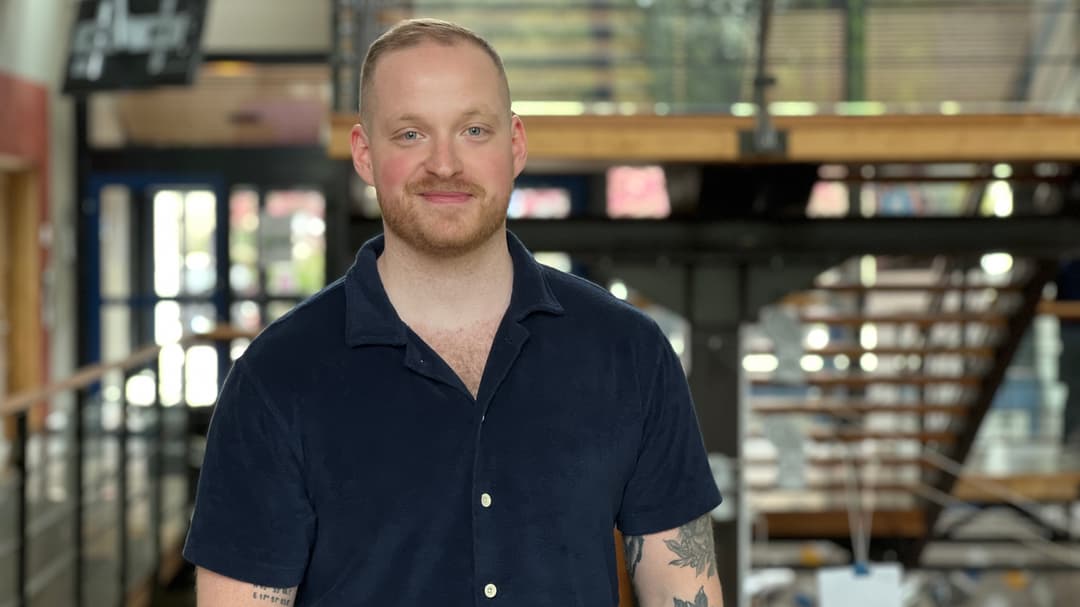 En man med mörk tshirt och tatueringar står i ett trapphus