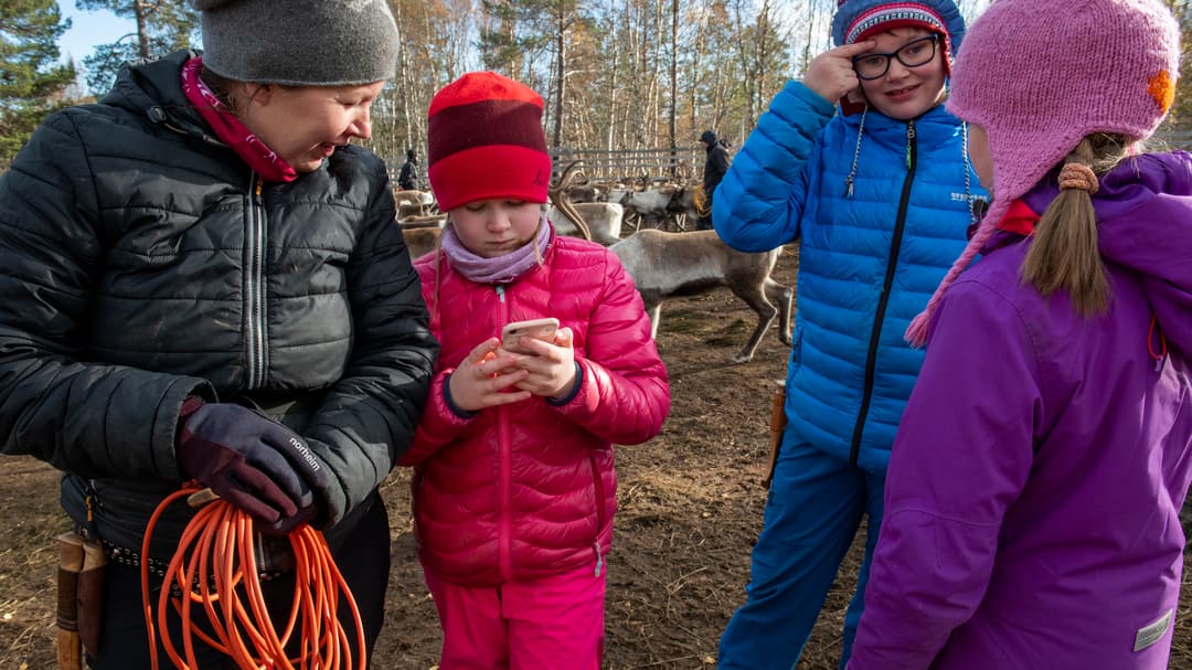 En flicka visar något på sin mobil för en kvinna.