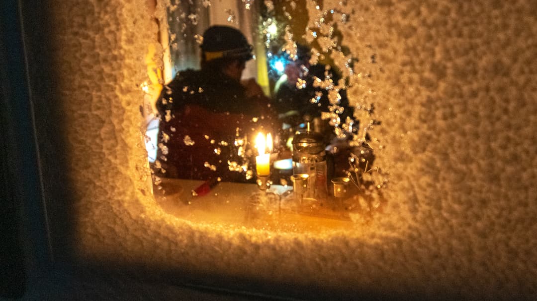 En person sitter i ljuset innanför ett igensnöat fönster.