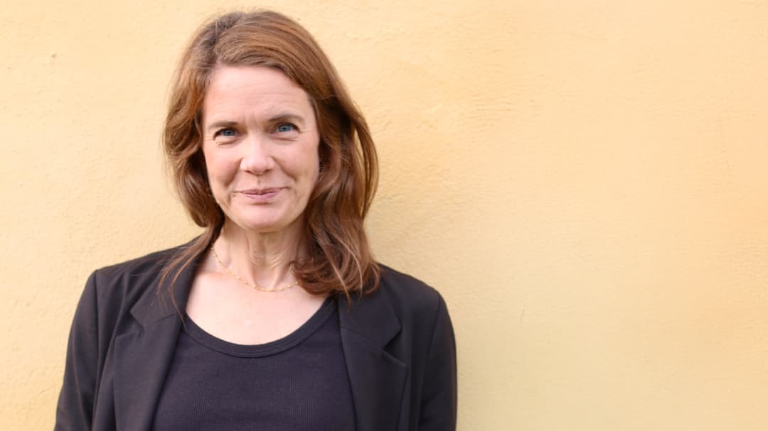 Portrait of a woman standing in front of a yellow wall.
