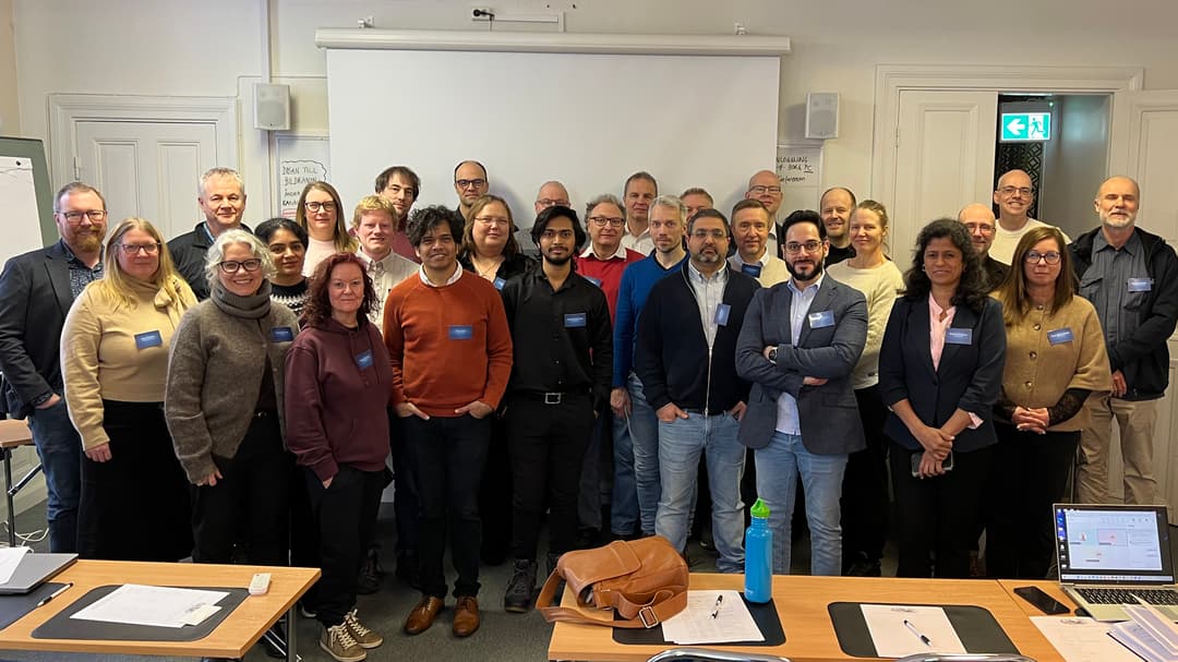 En grupp personer står tillsammans framför en whiteboardtavla.