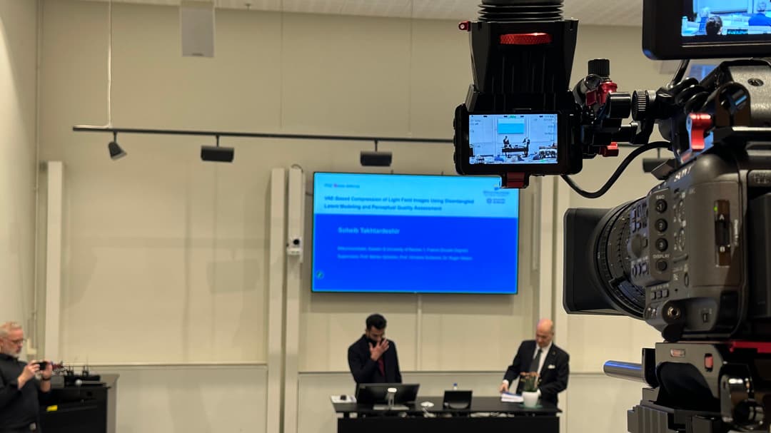 A camera whos filming two people on a stage