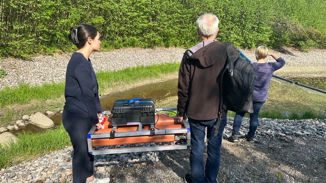 Två personer bär en liten orange båt som möter sedimentnivåer