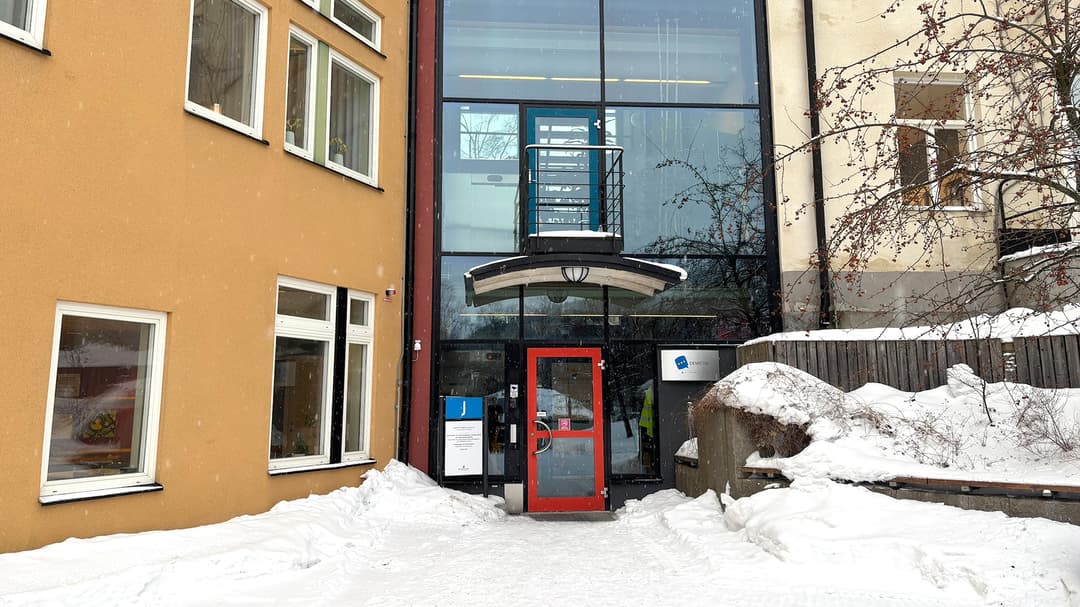 Husfasad i två olika färger, ett glasparti och en röd dörr.