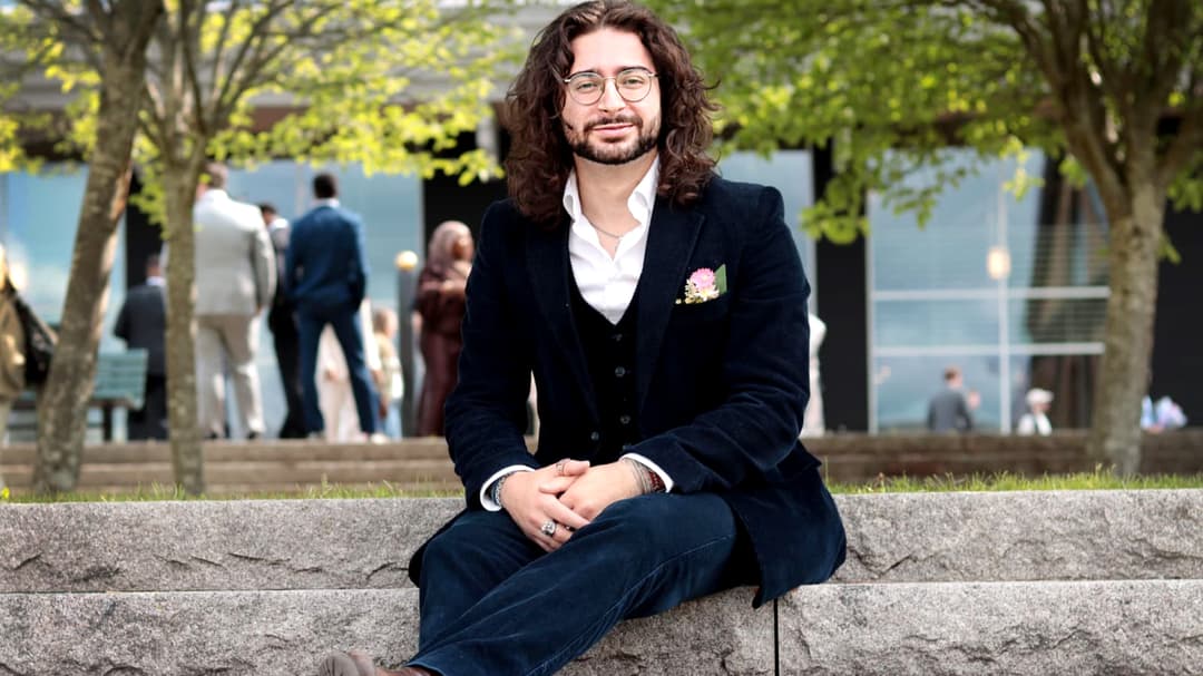 A man in a suit is sitting on stairs outside.