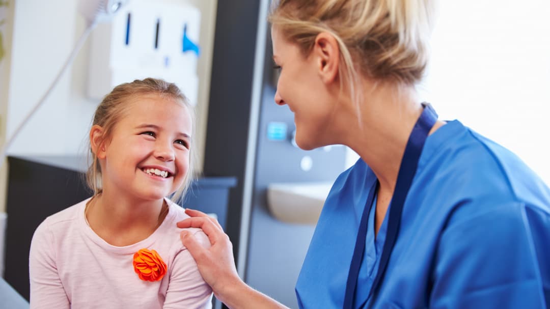 girl being reassured by nurse in hospital room.