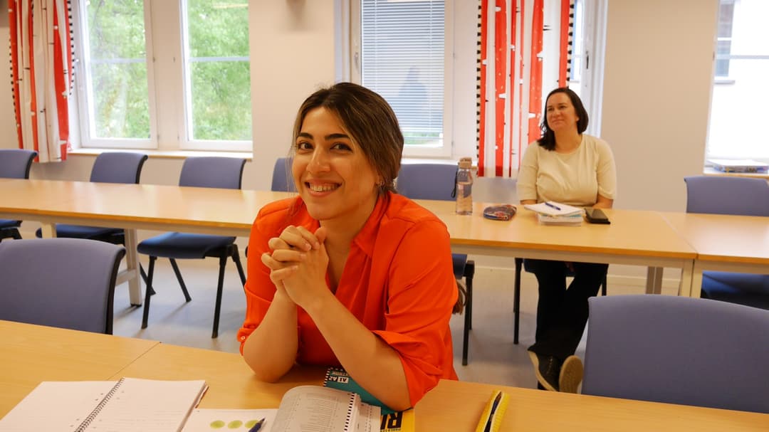 Två kvinnor sitter i en föreläsningssal med böcker framför sig.