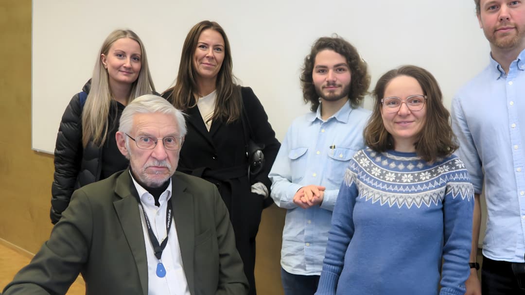Manlig lärare i ett klassrum omgiven av fem studenter