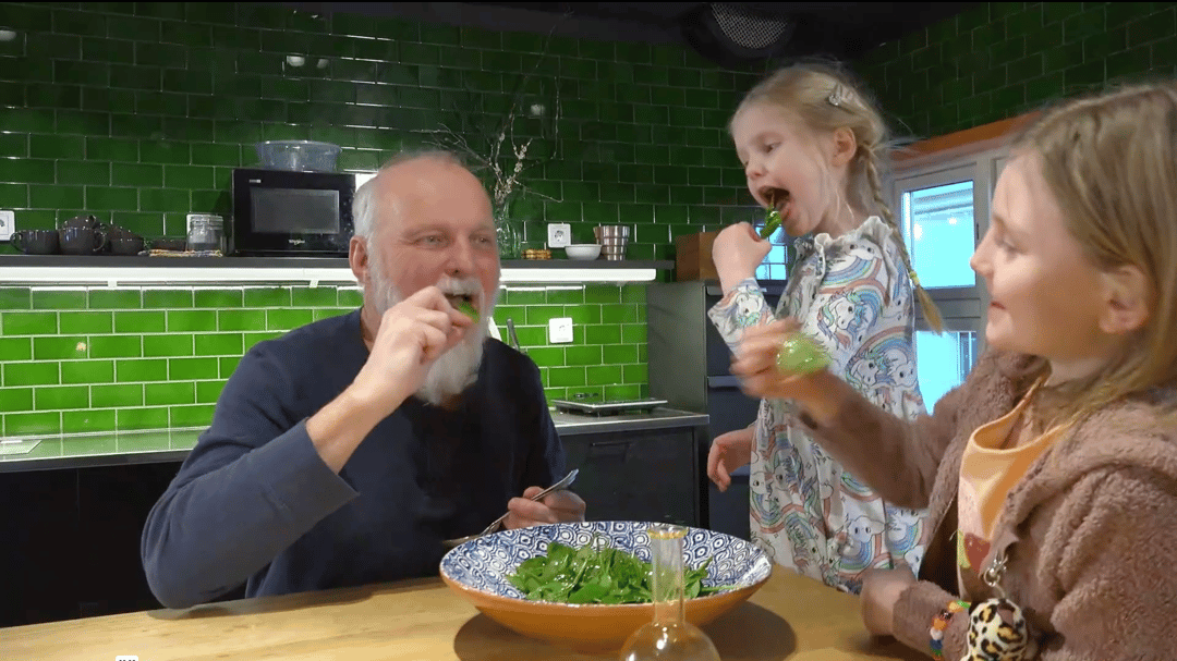 En man och två barn äter sallad