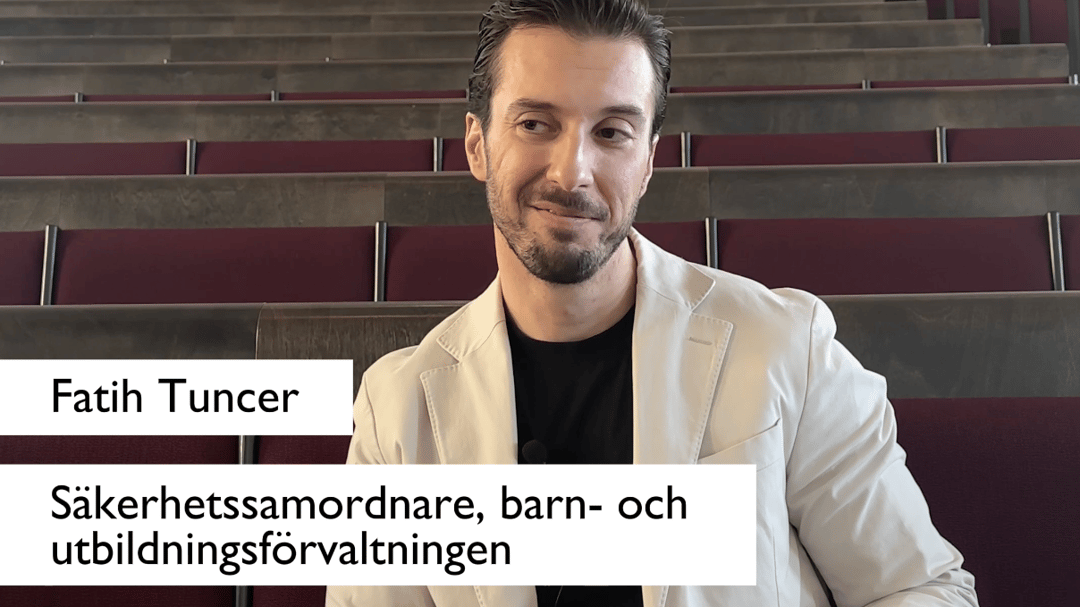 Man sitter med benen korsade och lutar sig bakåt under en intervju i en tom föreläsningssal.