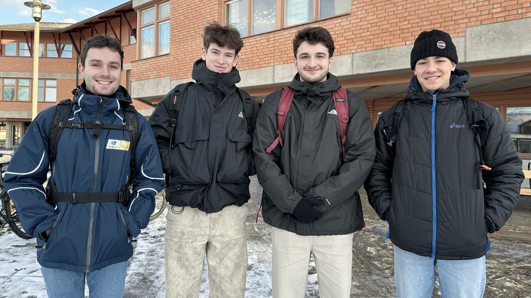 Fyra killar utomhus framför en tegelbyggnad.