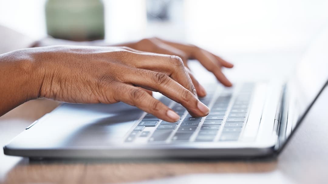 Two hands writing on a laptop