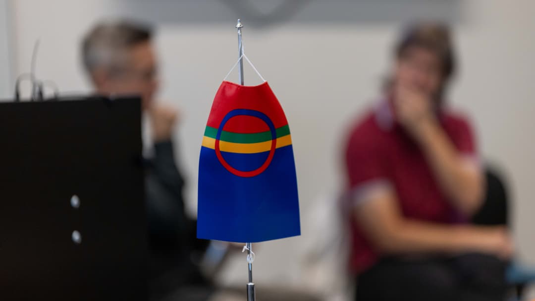 The Sami flag in the foreground and two people out of focus in the background