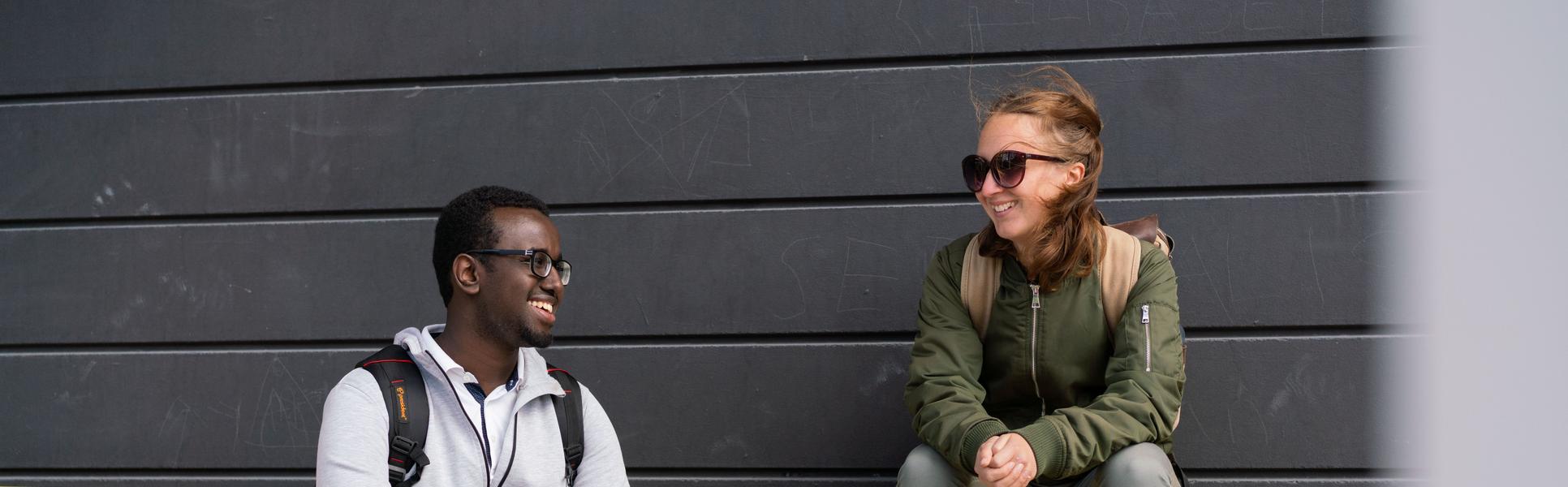 Two students sitting on a yellow bench.