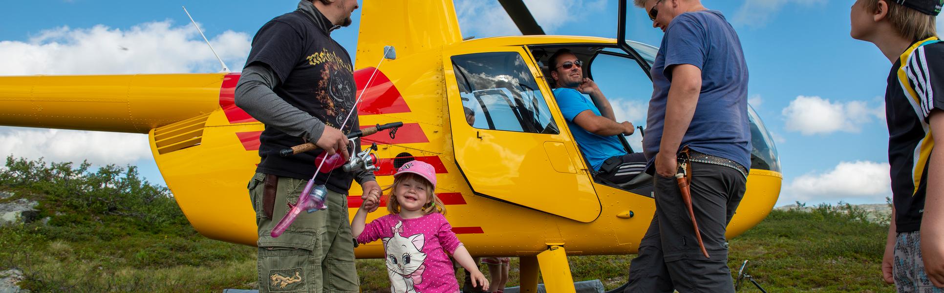 Två män och två barn intill en gul helikopter.