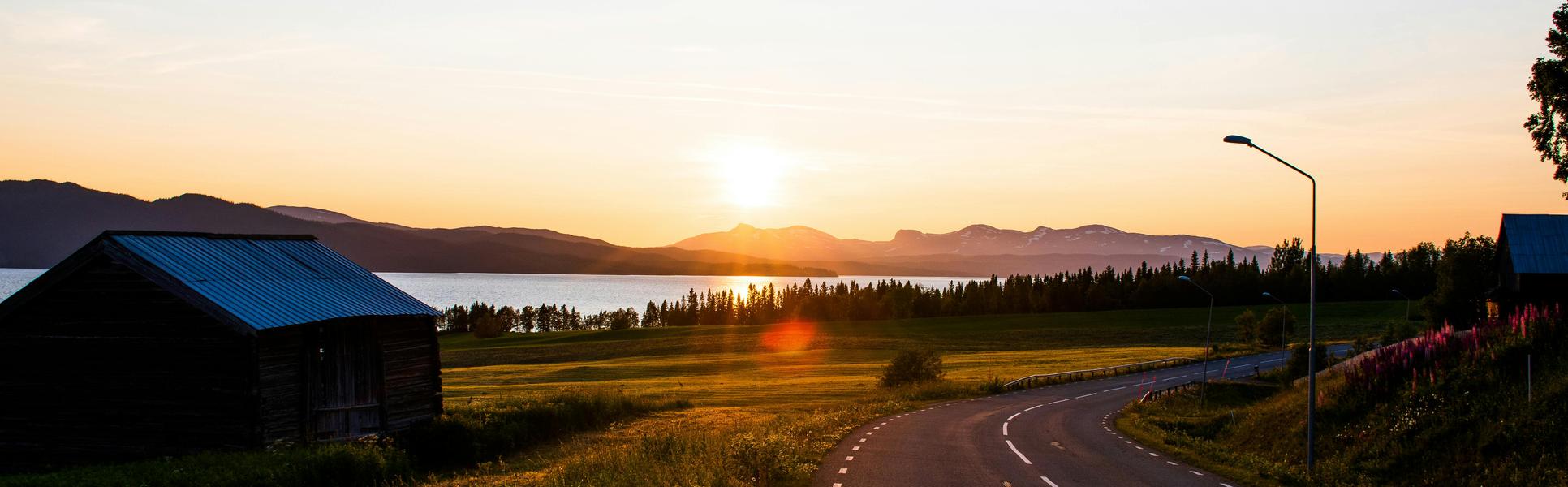 En landsväg med en lada i soluppgång.
