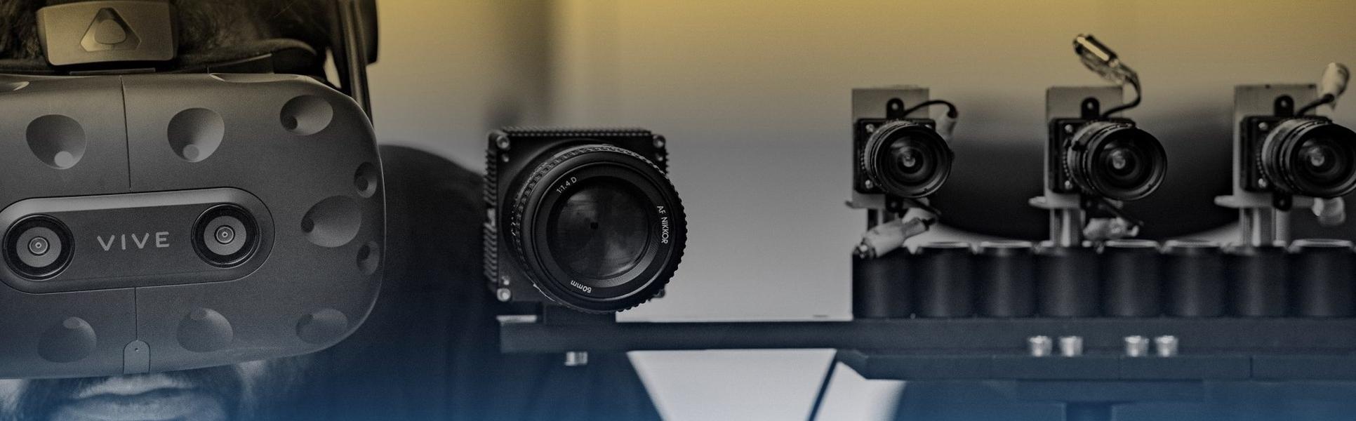 A man with a VR headset on standing next to a set up of smaller cameras.