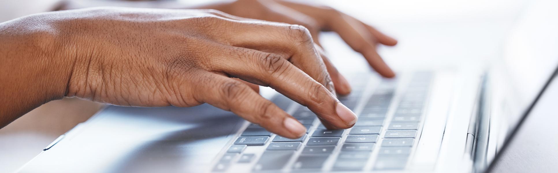Två händer som skriver på en laptop