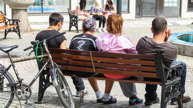Fyra ungdomar på en parkbänk på ett torg