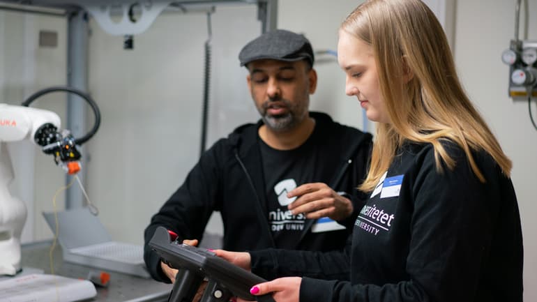 Man och kvinna som justerar en robotarm.
