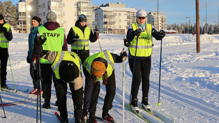 Skidåkare med reflexvästar i skidspår.