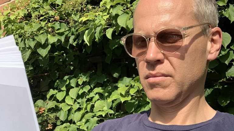 Per Becker sitter i solen och läser
