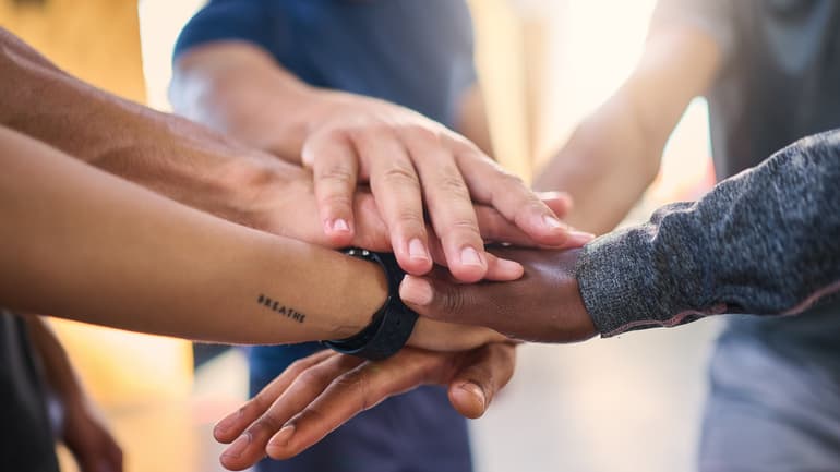Office employee group with hands in to show collaboration, trust and motivation for corporate job success.