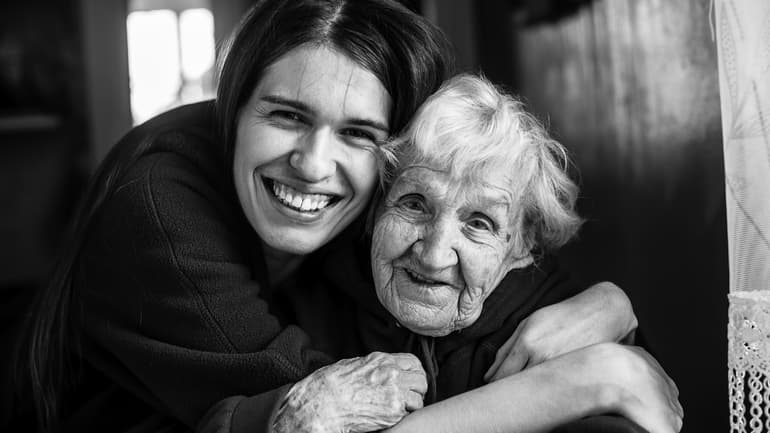 Young woman embracing his elderly mother. Black and white portrait.