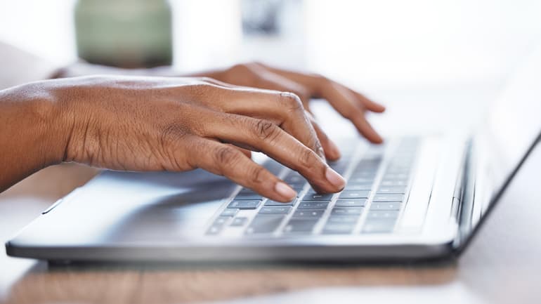 Two hands writing on a laptop