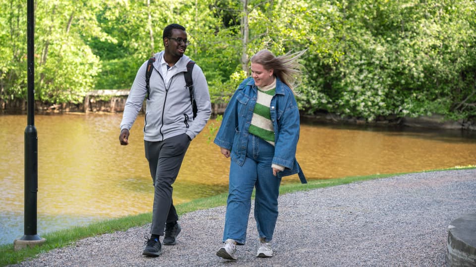 Två studenter som går längs en å vid campus Sundsvall.