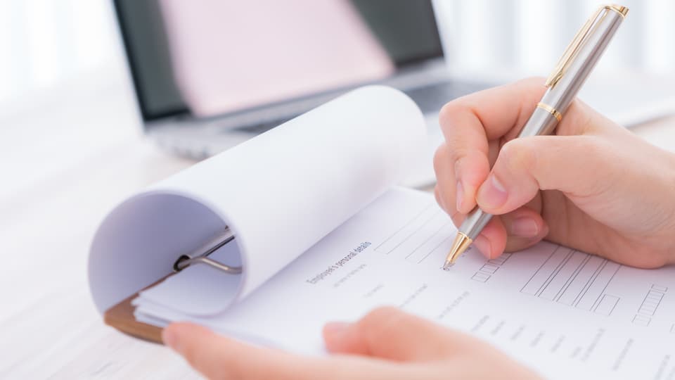 Hand with pen over assessment form.