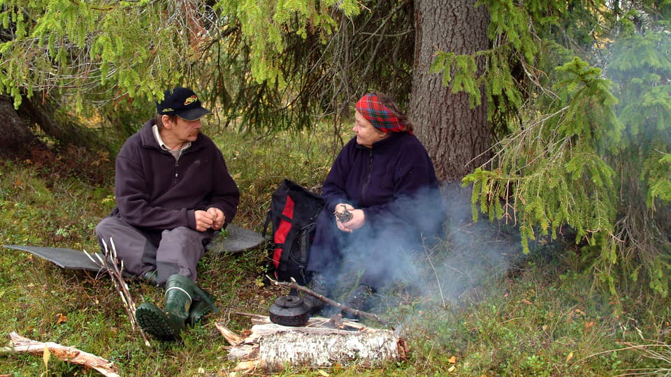 En man och en kvinna samtalar vid en kaffeeld under en gran.