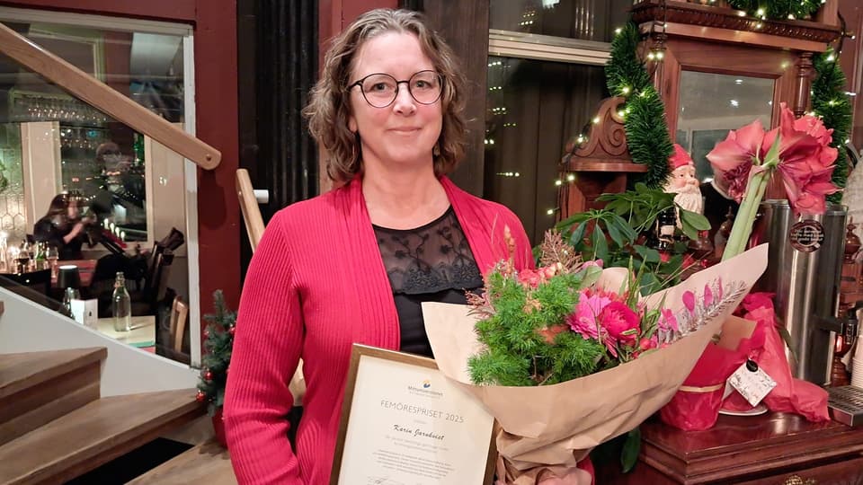 Kvinna i röd kavaj med diplom och blombukett i famnen