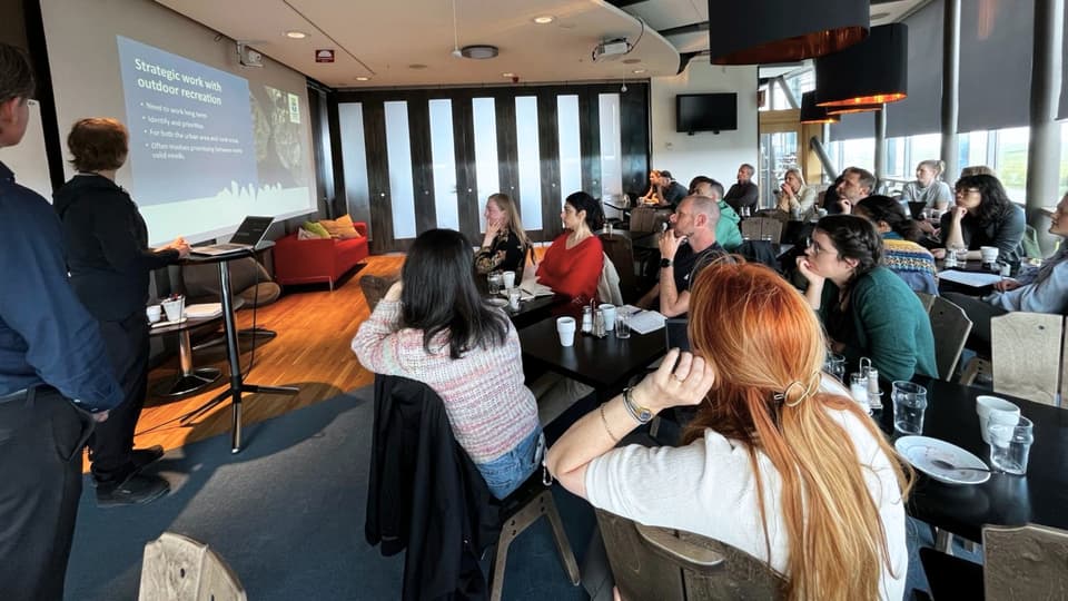 Students in a lecture room. A lecturer gives a lecture and looks at a big screen. 