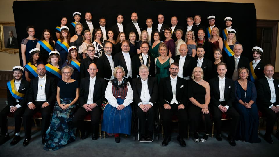 Gruppbild med högtidsklädda personer som sitter och står.