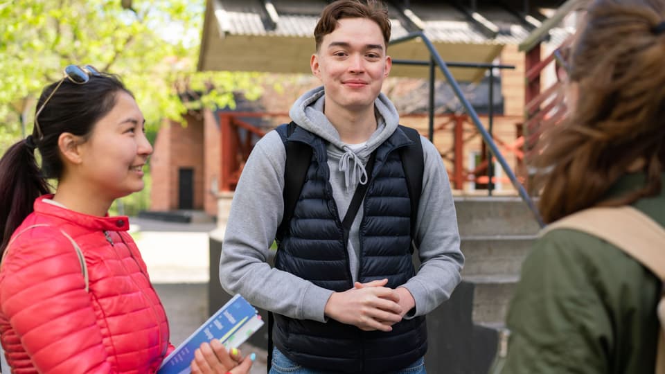  En grupp studenter som står och pratar med varandra utanför campus. 