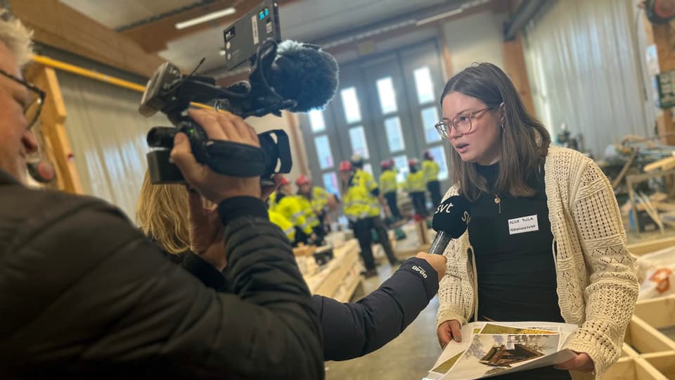 en kamera som filmar en intervju och en ung kvinna som pratar i en mikrofon