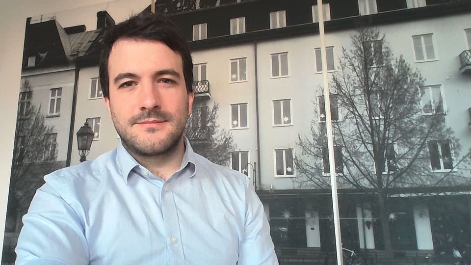  A man stands in front of a large photograph of a house facade.