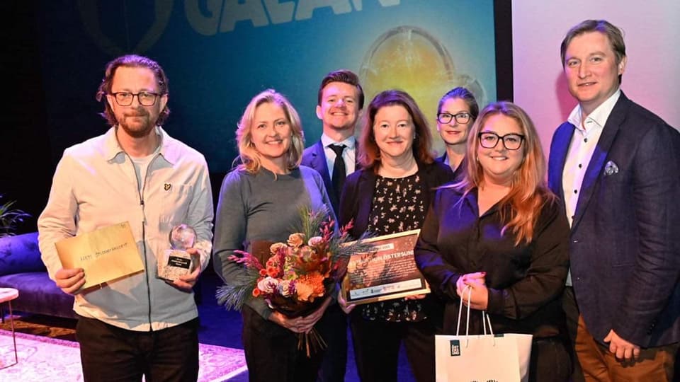 Fyra kvinnor och tre män med priser och blommor
