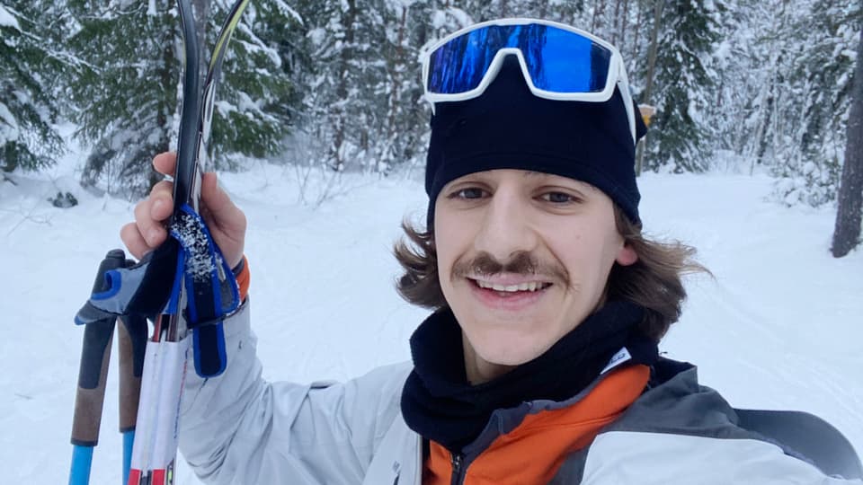 A man stands in a cross country skiing track.