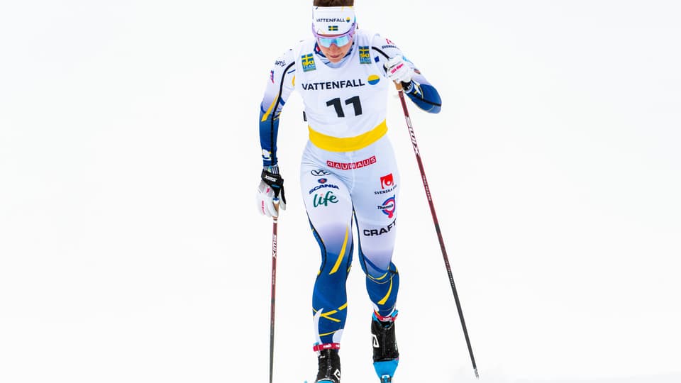 Kvinnlig längdskidåkare mot vit bakgrund.