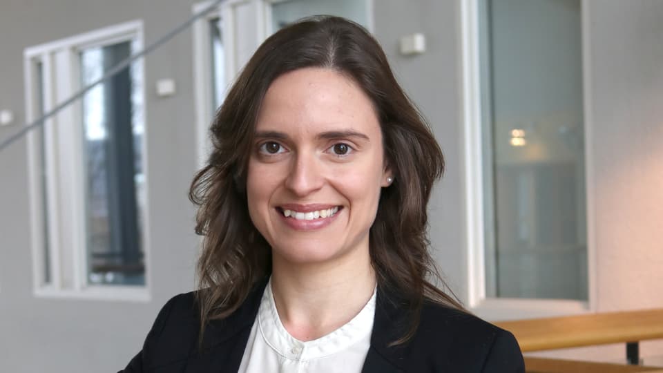 A woman looks into the camera and smiles.